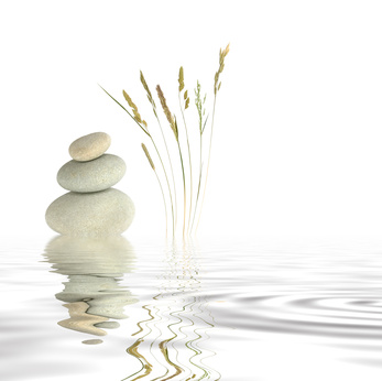 Abstract of three natural grey pebbles balanced on top of each other, with a selection of wild grasses to one side reflected over gray rippled water. Set against a white background.
